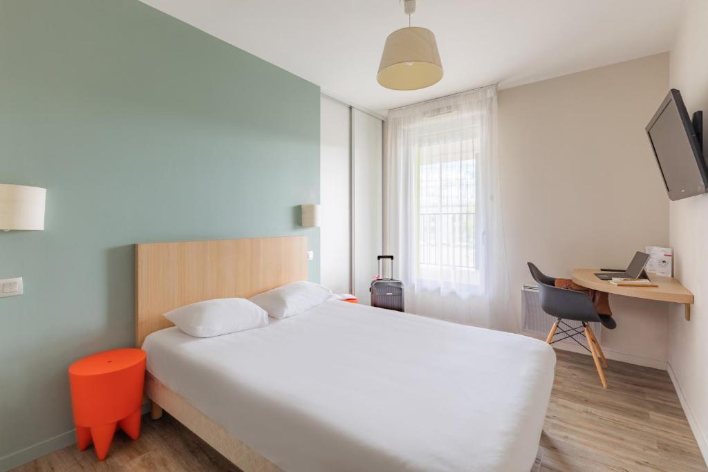 a bedroom with a large white bed and a desk at Appart’City Confort Tours in Tours