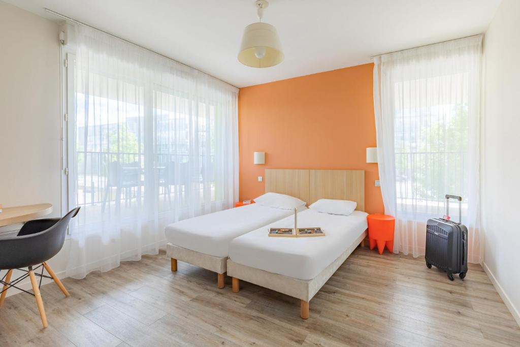 a hotel room with a bed and a desk and window at Appart’City Confort Tours in Tours