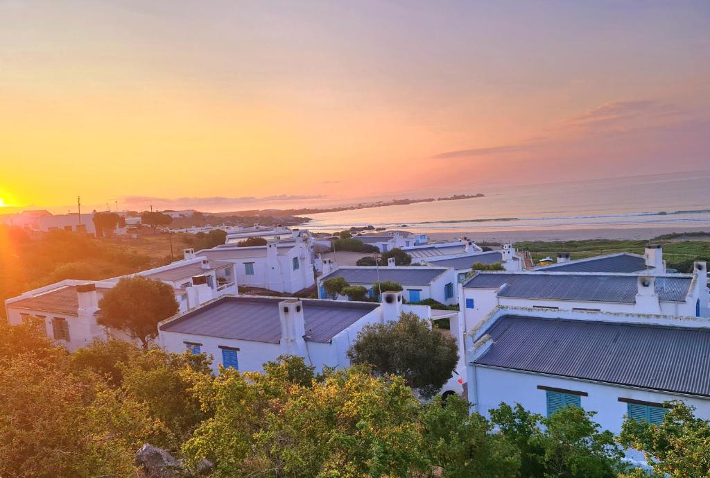 a group of white houses with the sunset in the background at Flamink Beach View Cottage in Paternoster in Paternoster