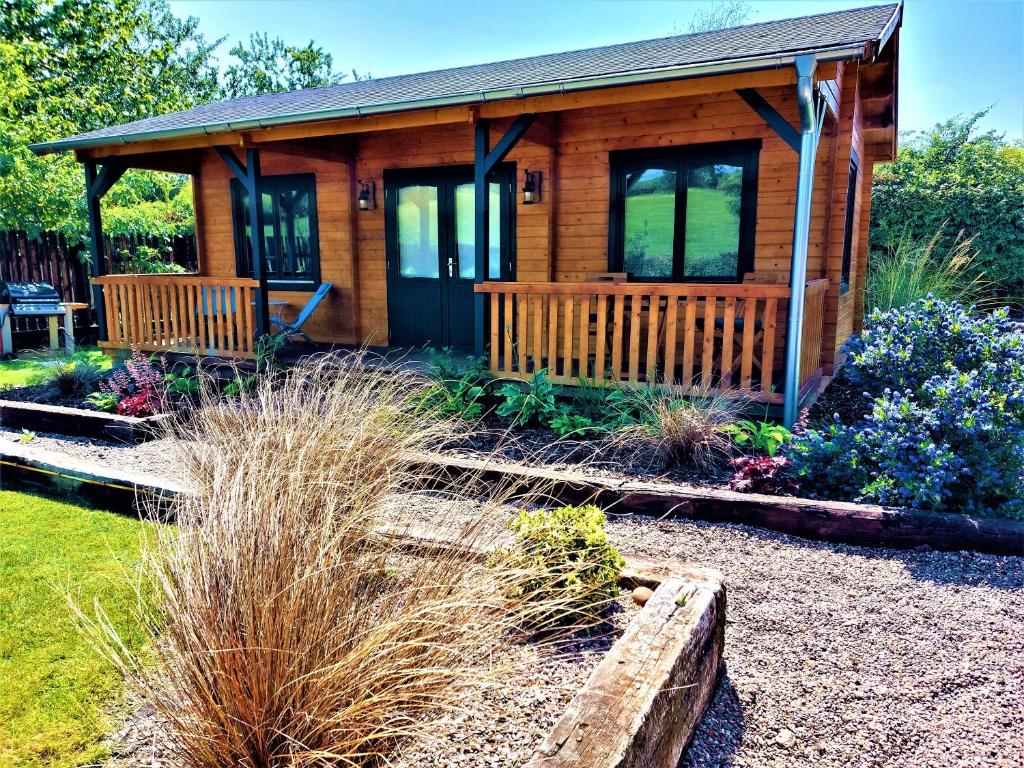 a log cabin with a garden in front of it at The Malvern Hills, Courtyard Cabins,Tom Cabin in Great Malvern
