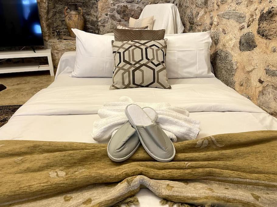 a bed with two pairs of slippers on it at LIVING IN A CAVE UNDER ACROPOLIS in Athens