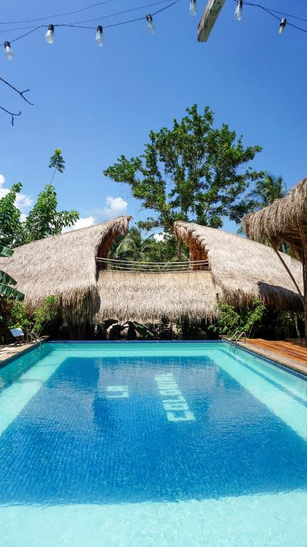 a swimming pool with two thatch huts at La Colonial Resort - Wellness Access Included in El Nido
