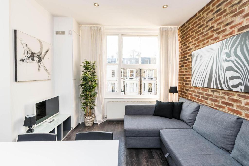 uma sala de estar com um sofá e uma parede de tijolos em Fantastic 1BD flat in the centre em Londres