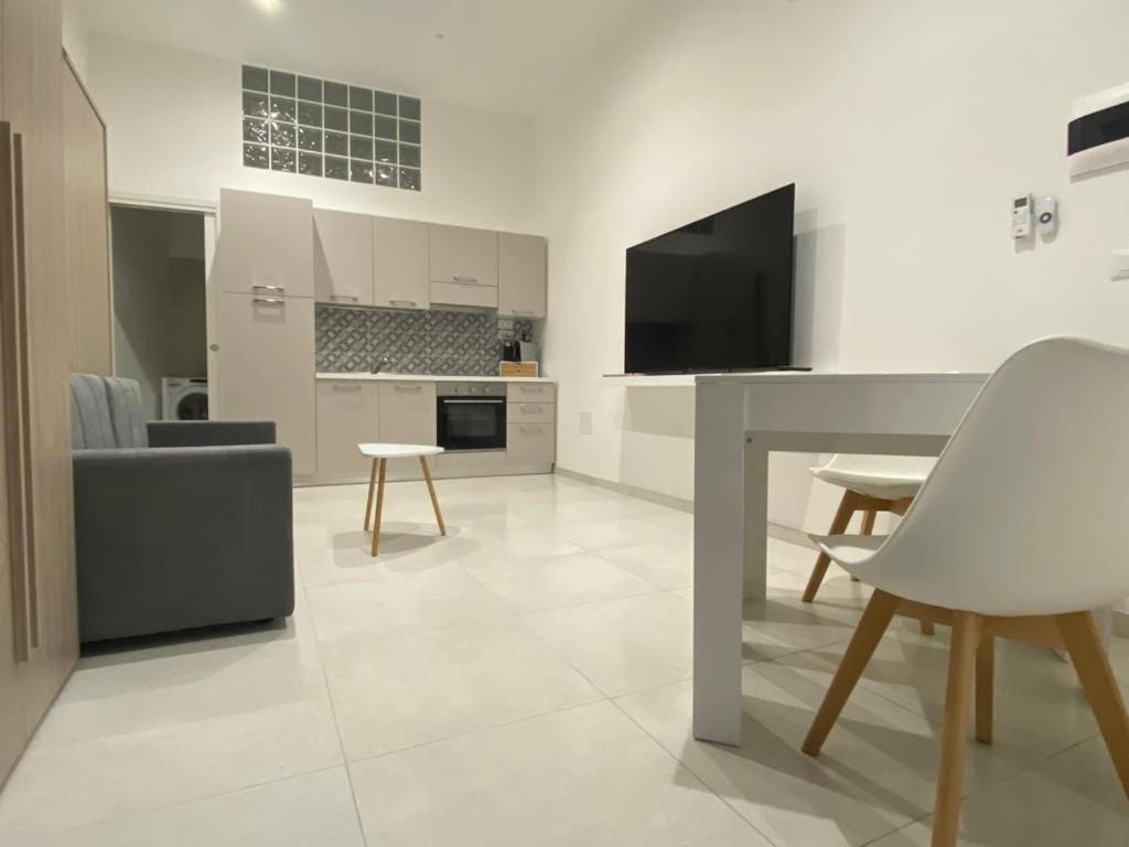 een keuken en een woonkamer met een tafel en een televisie bij Casa Don Saro in Giardini Naxos