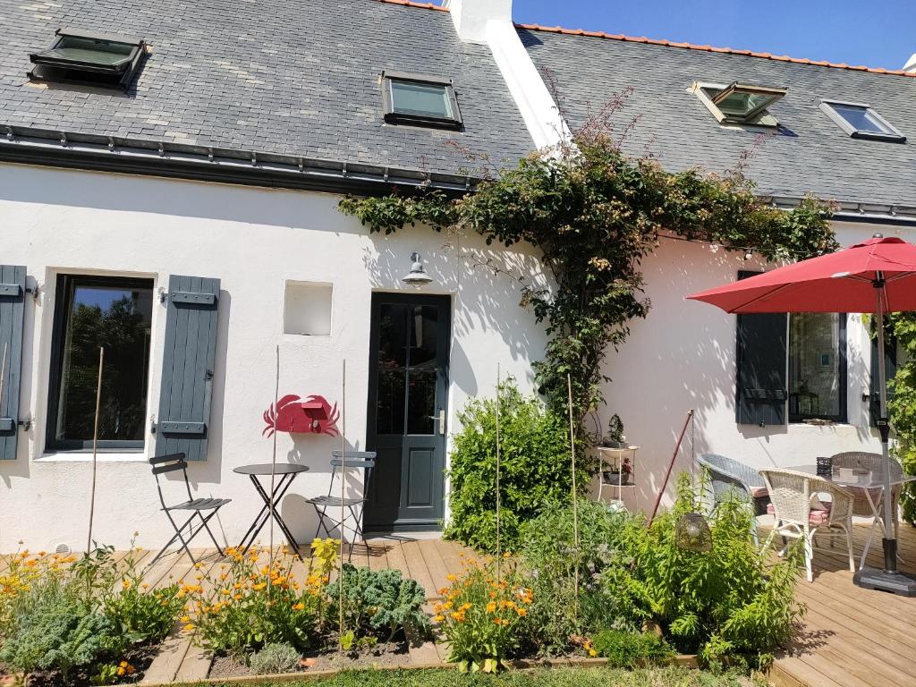 une maison blanche avec une terrasse dotée d'un parasol rouge dans l'établissement Le crabe rouge, à Groix