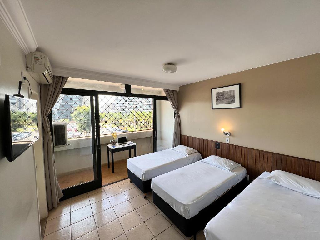 ブラジリアにあるホテル エル ピラールのベッド2台と窓が備わるホテルルームです。