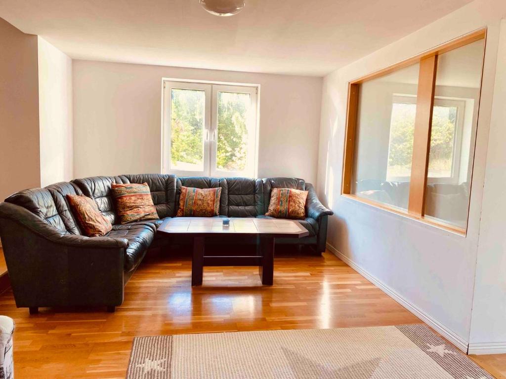 sala de estar con sofá de cuero negro y mesa en Bjurviks Villa - Flat 1, en Flen