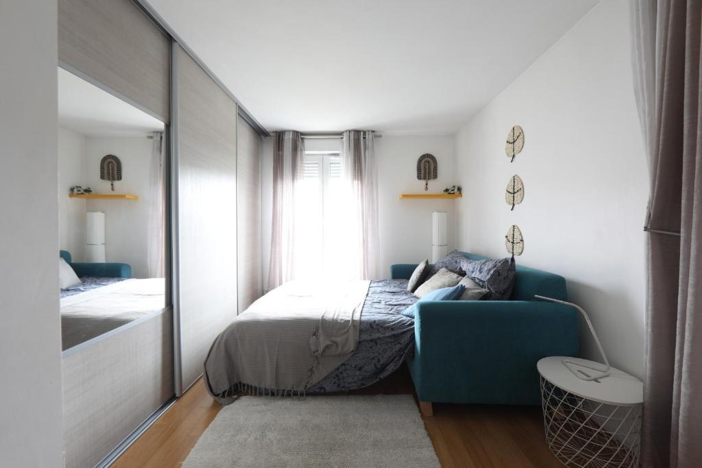 a bedroom with a bed and a blue chair at Charming 2br a 2 steps from the Stade de France - Welkeys in Saint-Denis