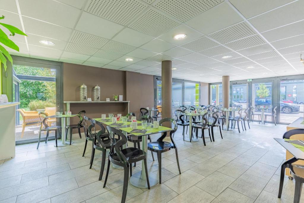 a dining room with tables and chairs and windows at Appart’City Confort Tours in Tours