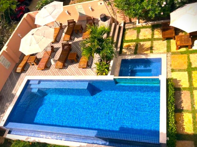 an overhead view of a swimming pool with chairs and umbrellas at Villa das Palmeiras Jeri in Jericoacoara
