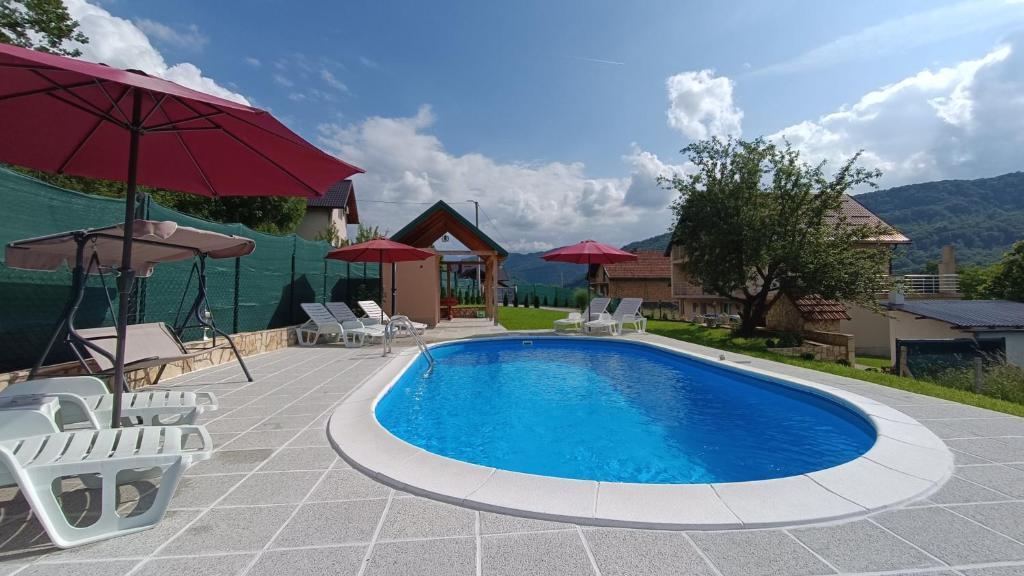 a pool with chairs and umbrellas on a patio at Villa Green Oasis With Pool in Sarajevo