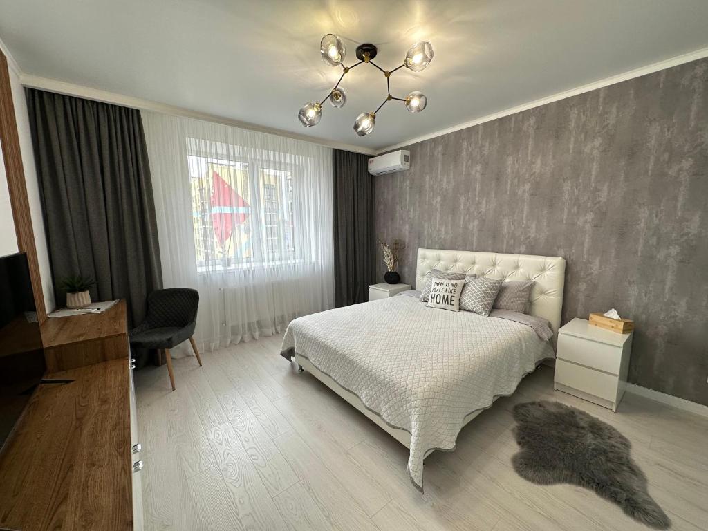 een slaapkamer met een wit bed en een kroonluchter bij Comfort Apartment in Vinnytsya