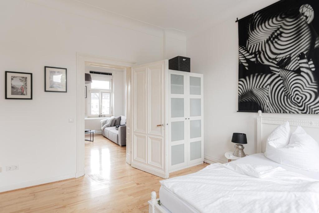 een witte slaapkamer met een bed en een woonkamer bij LULEX I - Luxus Apartment Krefeld Alexanderplatz in Krefeld
