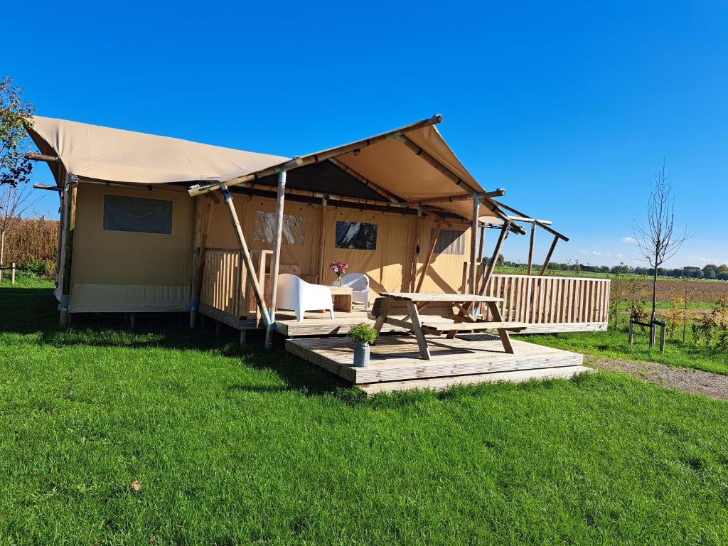 ein Haus mit einem Zelt auf einem Grasfeld in der Unterkunft De Hazelaarshof- luxe XL-glampingtent (7-8 personen) nabij De Millingerwaard in Kekerdom