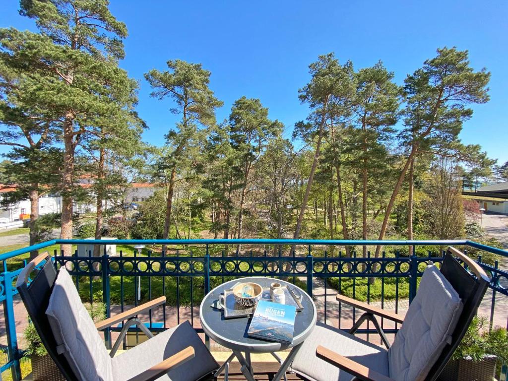 une table et des chaises sur un balcon arboré dans l'établissement Kurparkresidenz Baabe - FeWo 14, à Baabe