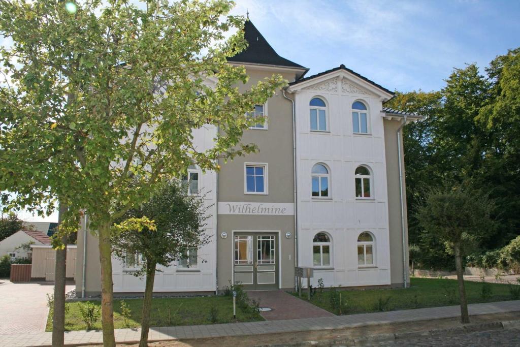 ein großes weißes Gebäude mit einem Baum davor in der Unterkunft Villa Wilhelmine - FeWo 02 Wilhelm in Ostseebad Sellin