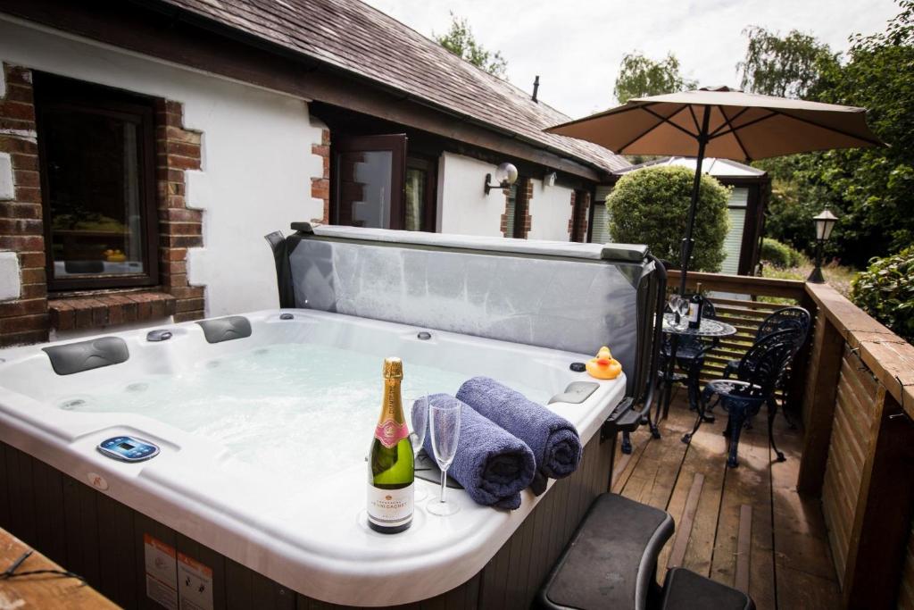 a bath tub with a bottle of champagne in it at The Stables at Country Ways in Atherington
