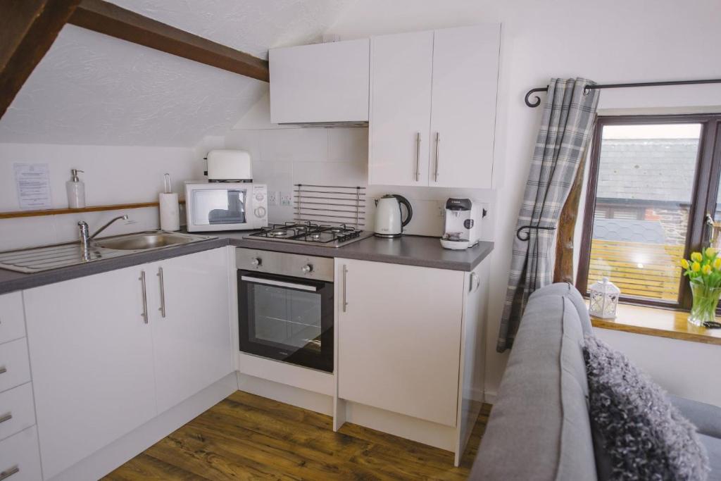 a kitchen with white cabinets and a sink and a microwave at The Dray at Country Ways in Atherington