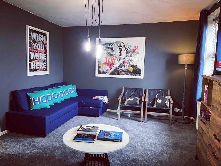 a living room with a blue couch and a table at Chester/Handbridge sleeps 9 + Netflix in Hough Green