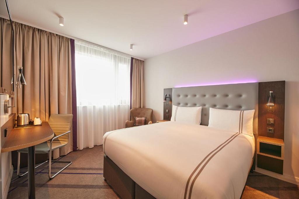 ein Hotelzimmer mit einem großen Bett und einem Schreibtisch in der Unterkunft Premier Inn Karlsruhe City Am Wasserturm in Karlsruhe