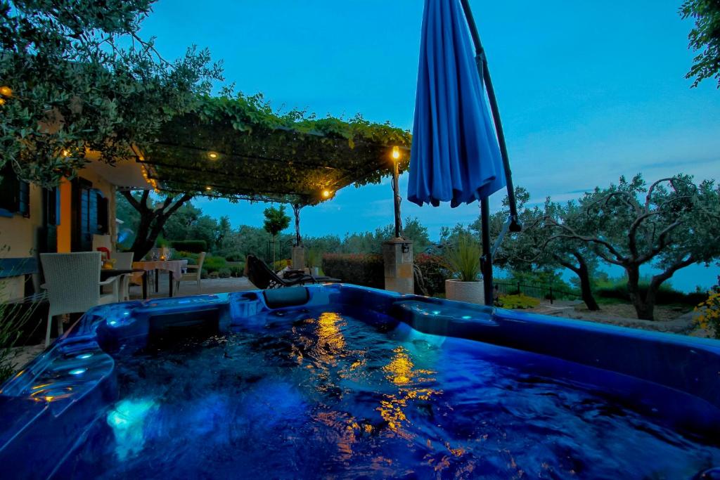 a swimming pool with an umbrella in a backyard at Holiday home Oaza in Baška Voda