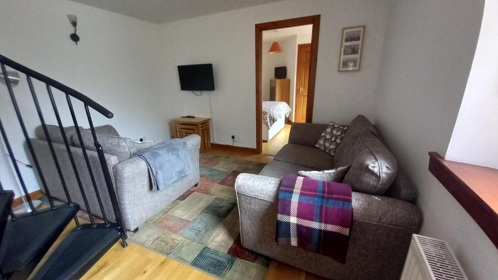 uma sala de estar com um sofá e uma televisão em North End The Cottage em Nairn