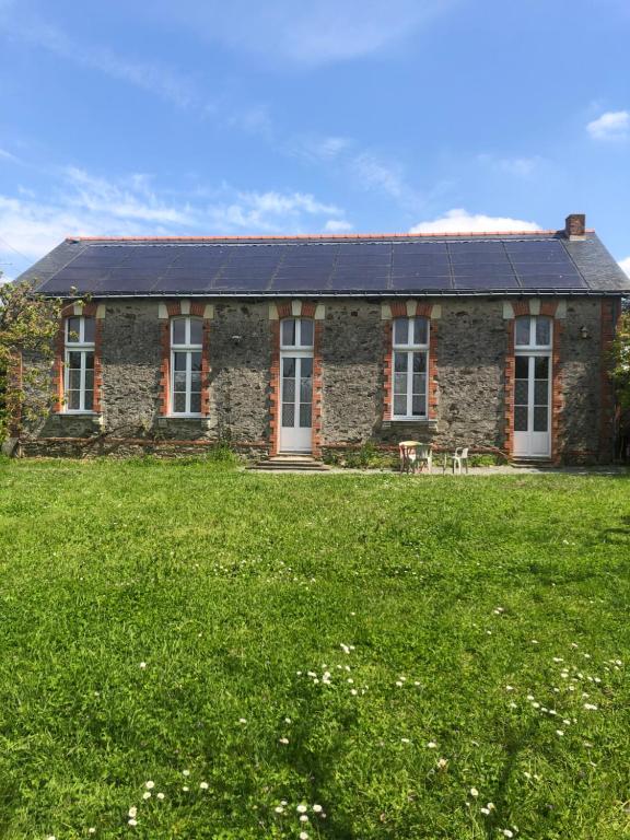 ein Steinhaus mit einem Sonnendach auf einem Grasfeld in der Unterkunft Gîte -Belle Maison dans une ancienne école-Tarif réduit hors WE ! in Chanzeaux