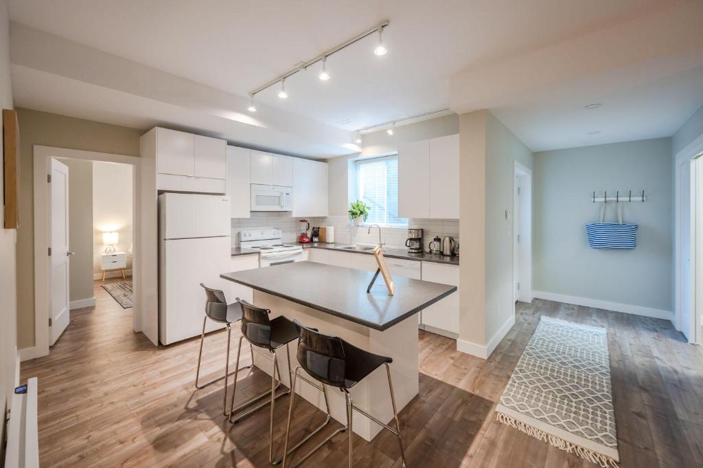 a kitchen with white cabinets and a island with chairs at Evergreen Condo by Leavetown Vacations in Penticton