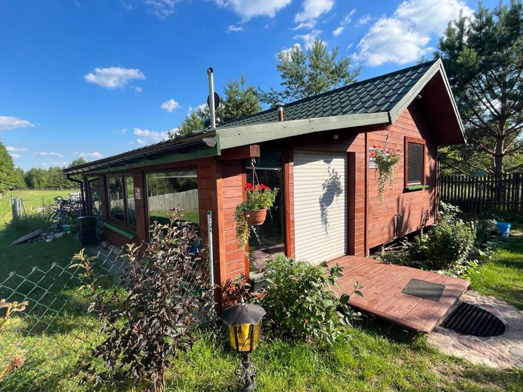 una casa pequeña con porche y terraza en Domek nad brzegiem jeziora Śniardwy z własnym pomostem, zejściem do wody i przecudnym widokiem na jezioro, en Zdory