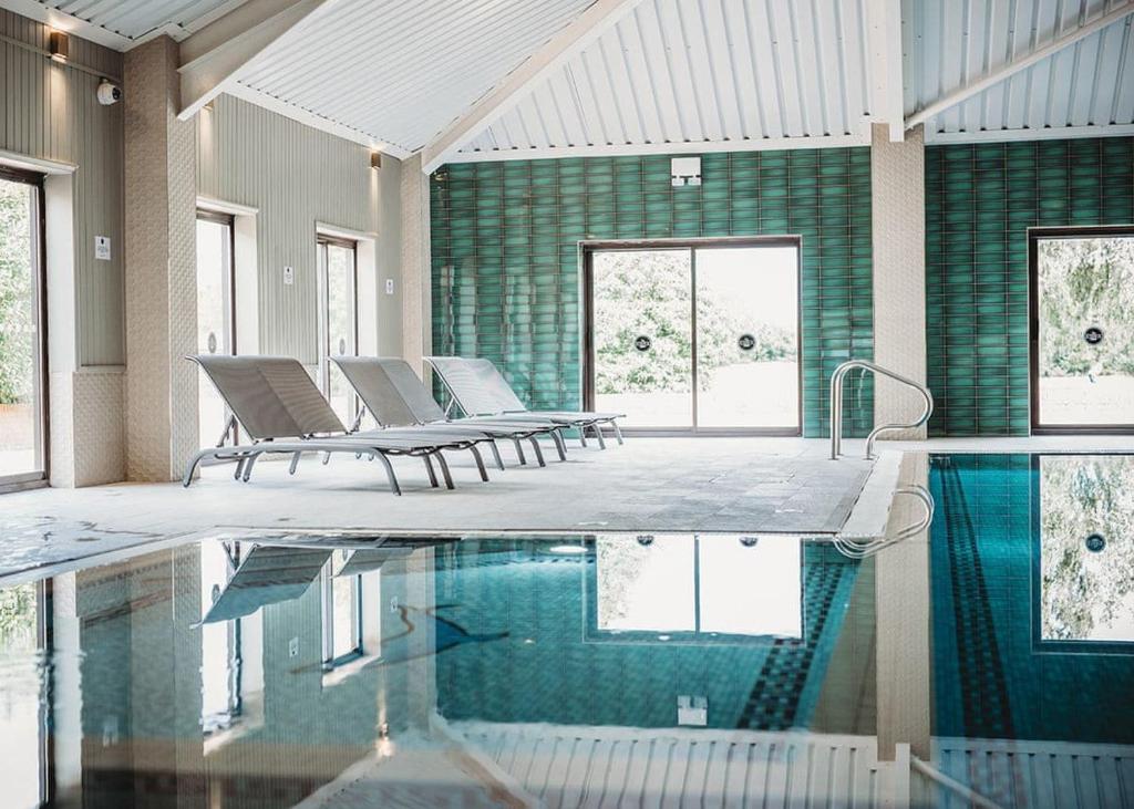 a room with a pool with chairs and windows at The Essex Golf And Country Club 