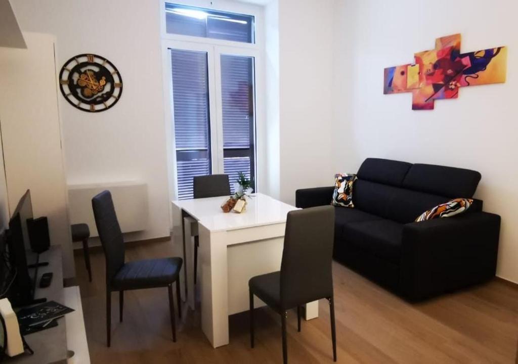 uma sala de estar com um sofá, uma mesa e cadeiras em CASA LOSURIELLO em Triggiano