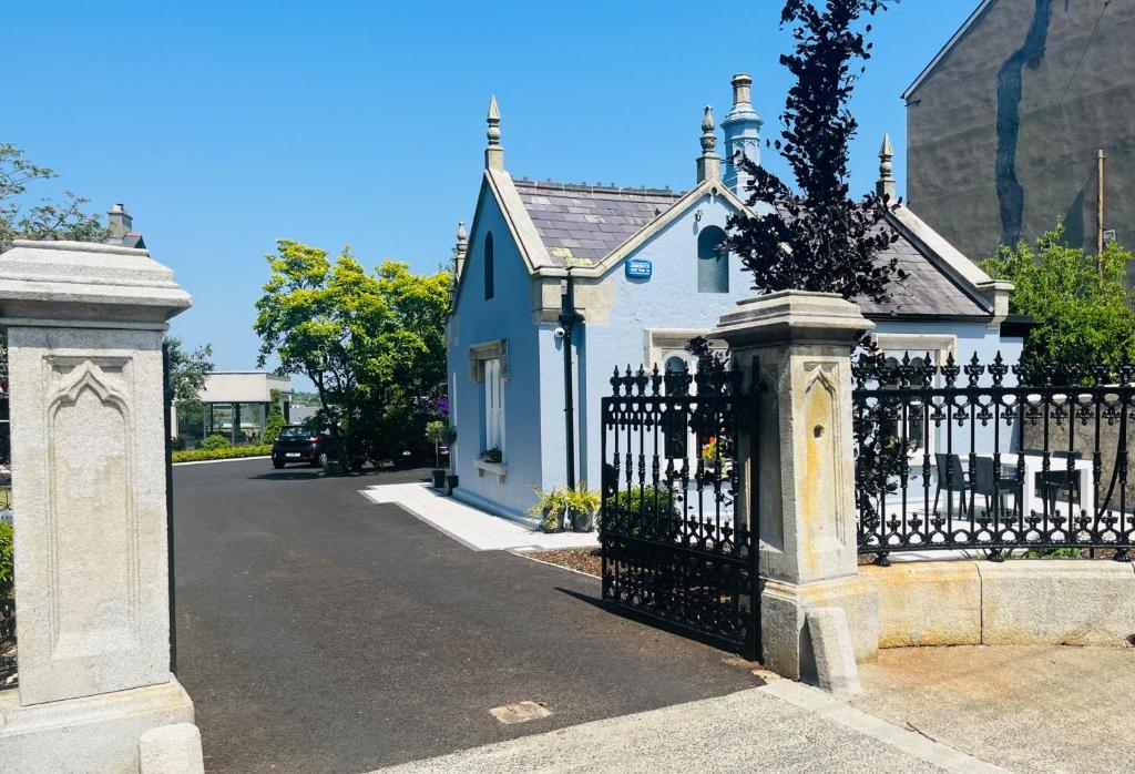 a white house with a black gate in a street at Wellington Cottage in Wexford