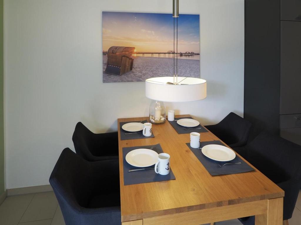 a wooden table with plates and a lamp and chairs at Kirschgarten 2 - Möwennest in Kellenhusen