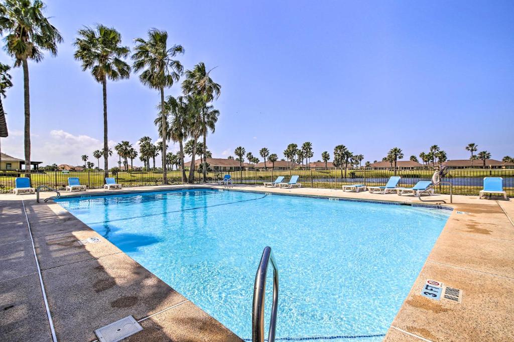 a large swimming pool with chairs and palm trees at Laguna Vista Vacation Rental with Pool Access! in Laguna Vista
