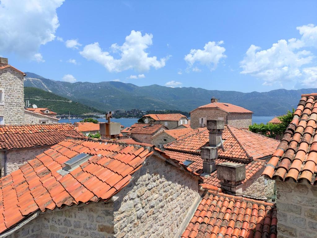a view of roofs of buildings with mountains in the background at Attic Old Town Apartment in Budva