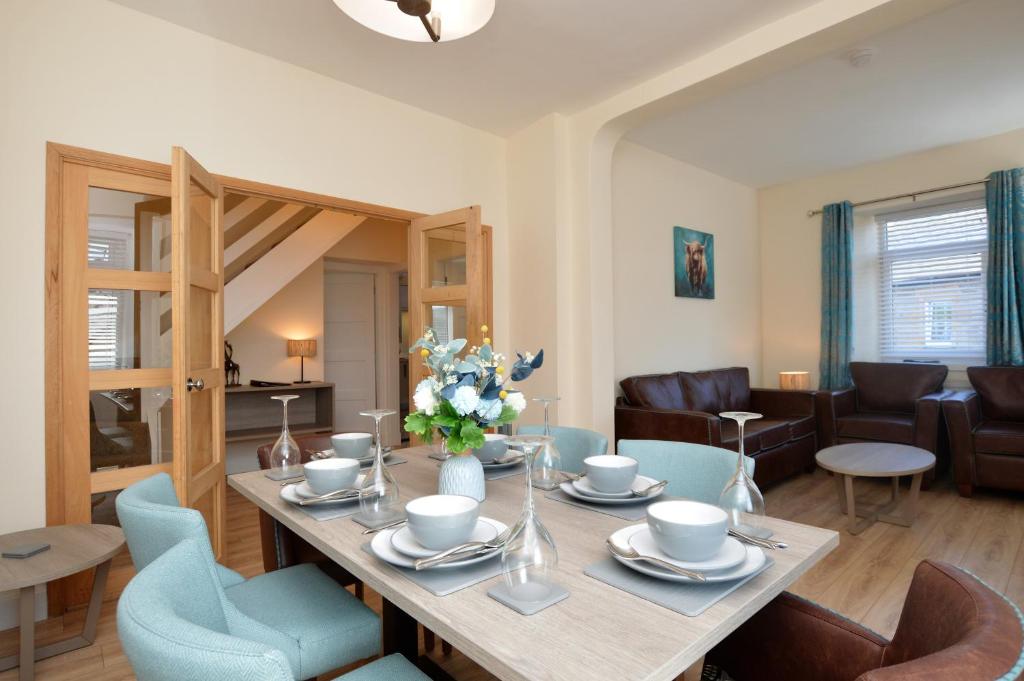 a living room with a wooden table and blue chairs at Burnside in Tighnabruaich