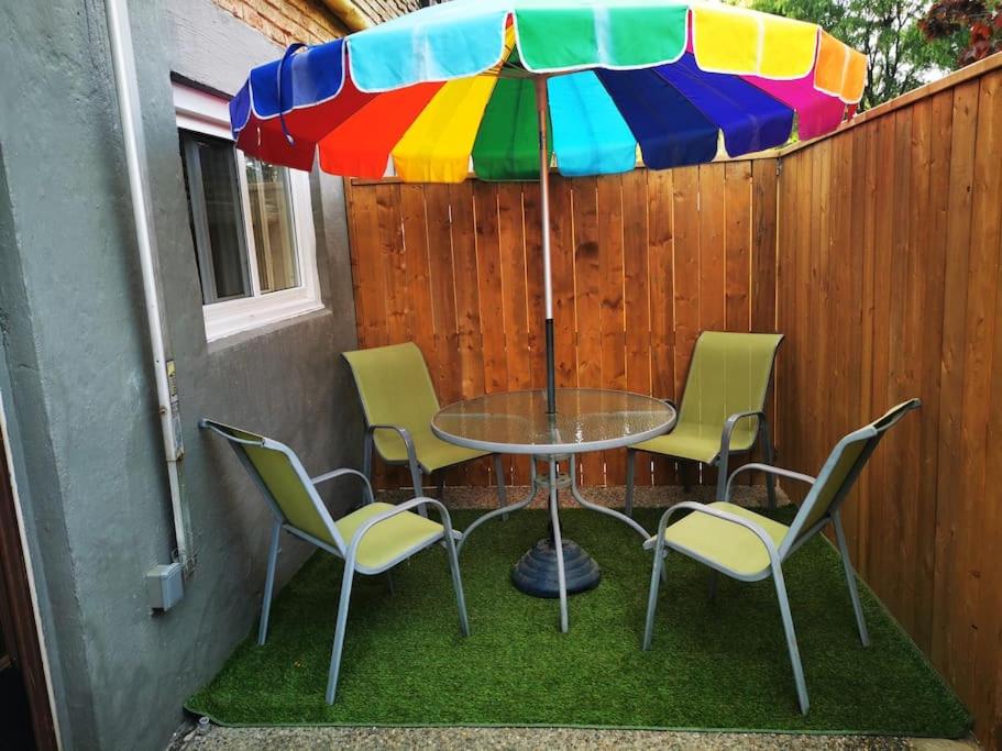 uma mesa com cadeiras e um guarda-sol colorido em Patio privé, hébergement équipé et spacieux. em Hamilton