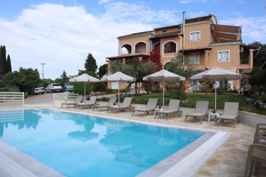 a pool with chairs and umbrellas in front of a house at Pasiphae Holiday Apartments in Kontokali