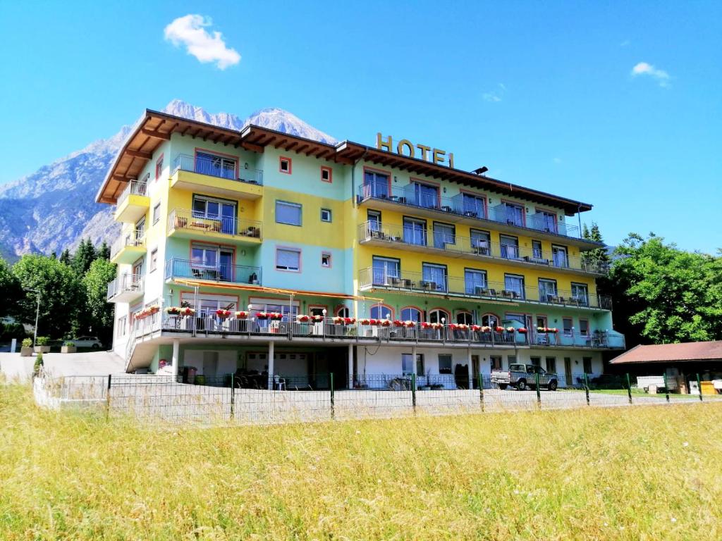 a large yellow hotel with a mountain in the background at Hotel Martina in Telfs