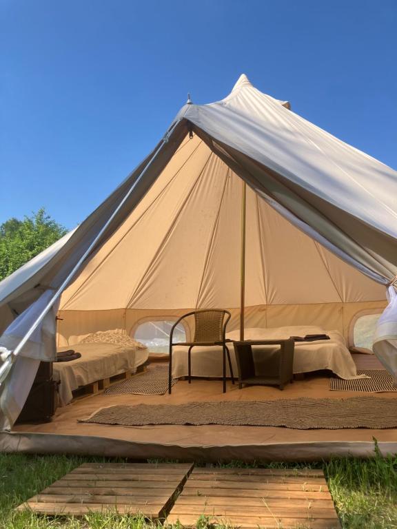 une tente en toile avec 2 lits et 2 chaises dans l'établissement Mazury Glamping Kruklanki Polana Życzeń, à Kruklanki