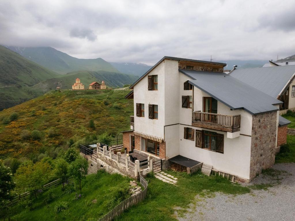 a house on a hill with mountains in the background at Snow Time Cottage in Gudauri