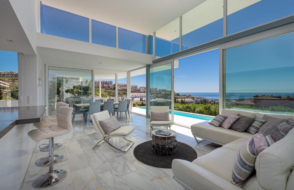 a living room with a couch and chairs and glass windows at Villa Dona Julia 2410 Golf and Sea views in Casares