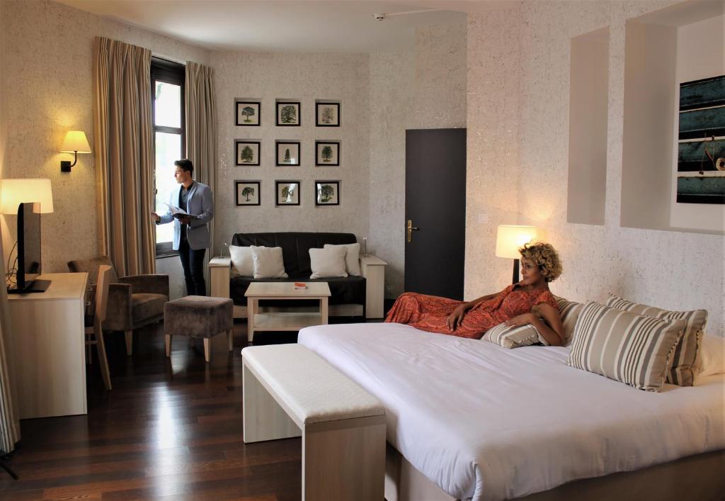 een vrouw op een bed in een hotelkamer bij Logis Les Loges du Parc in La Roche-Posay