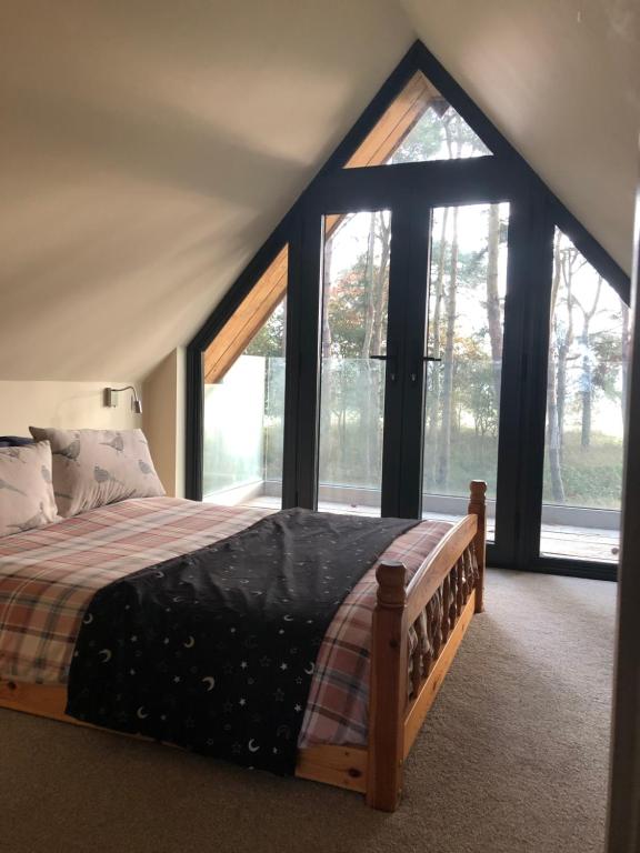 a bedroom with a bed in a room with windows at Toad Hall in Grimston