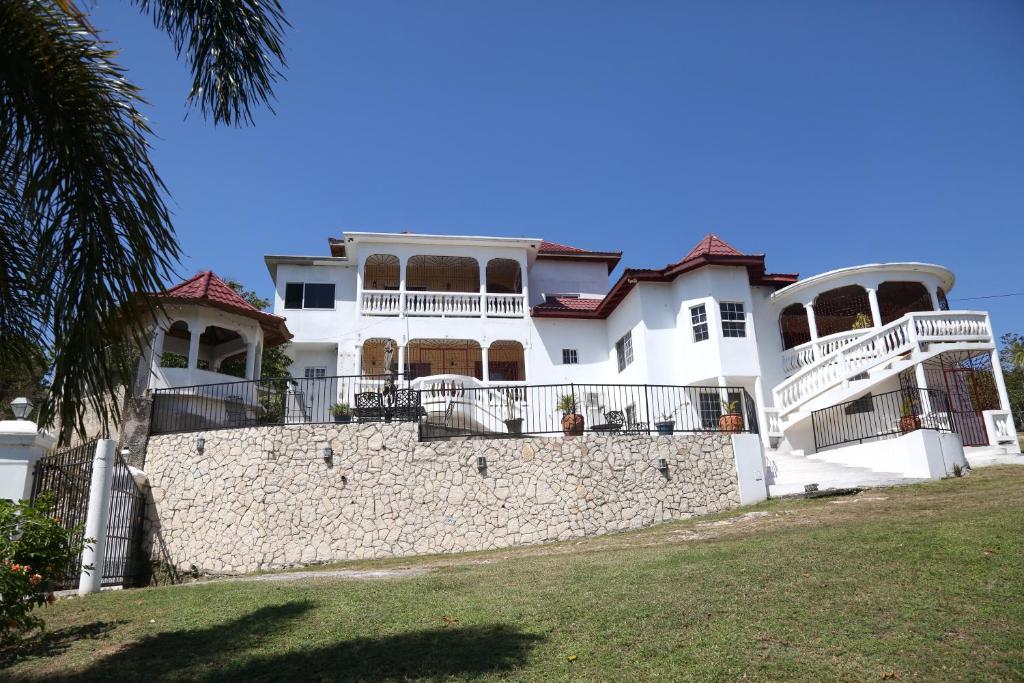 a large white house behind a stone wall at Jannetta's @Whimhill Bed & Breakfast in Negril