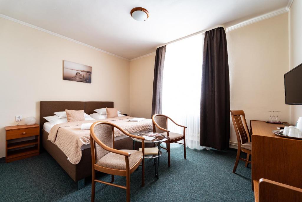 pokój hotelowy z łóżkiem, stołem i krzesłami w obiekcie Hotel Panorama w Pilznie