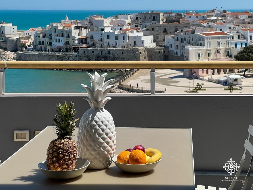 a table with two bowls of fruit on a balcony at Infinito - Attico sul mare in Vieste