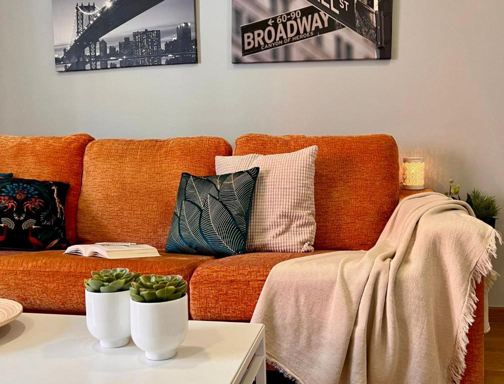 a living room with an orange couch with pillows on it at Rías Altas Home Sada in Sada