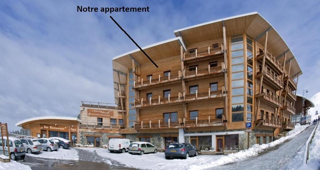 a large building with cars parked in the snow at CHAMROUSSE T2 Sud Ski Rando et Vtt aux pieds Les balcons du Recoin in Chamrousse