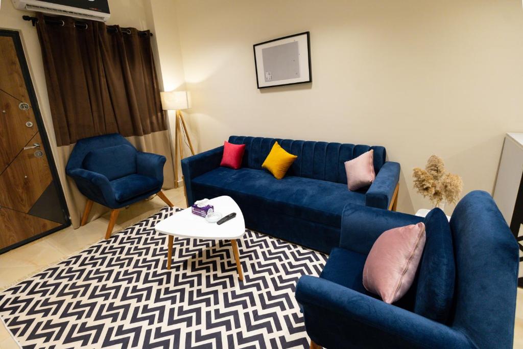 uma sala de estar com um sofá azul e duas cadeiras em Marron studios 2 new no Cairo